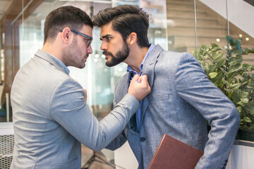Business conflict between two business men in formal-wear in office. Boss and employee with aggressive expression fight.