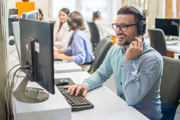 Confident male customer support operator with headset working in call center.
