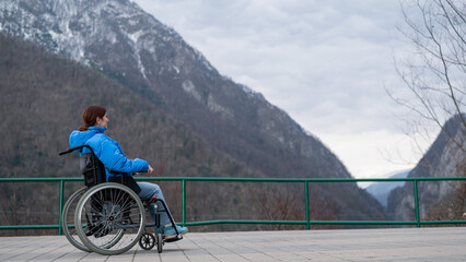 A woman in a wheelchair on a point view admires the high mountains. Thrust to life. 