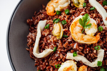 delicious red rice with shrimps and seafood on a white background
