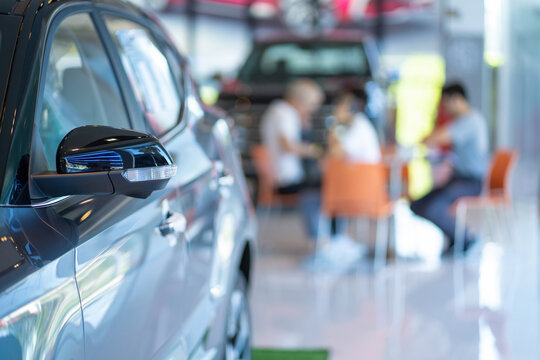 New modern car and young professional salesman demonstrating document to customer buying new car in dealership. Selective focus.