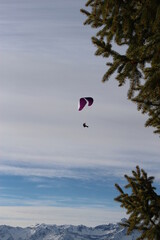 Paraglider in winter soaring over the swiss alps high in the sky. Concept for extreme winter...