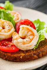 delicious Italian bruschetta with shrimps on a black wooden rustic background