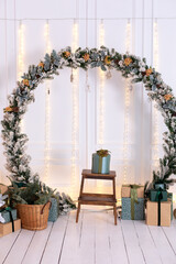 Christmas wreath on wall room. Festive New Year decor home. Scandinavian style. Interior design of living room with a large Xmas spruce green wreath, gifts boxes and basket with branches fir and pine.