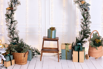 Christmas wreath on wall room. Festive New Year decor home. Scandinavian style. Interior design of living room with a large Xmas spruce green wreath, gifts boxes and basket with branches fir and pine.