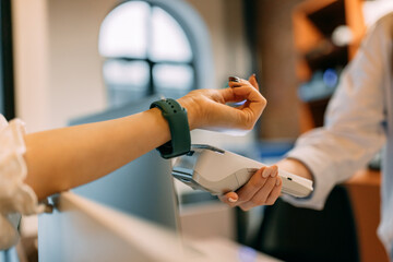 Costumer using a smart watch to pay, putting it close to the device,