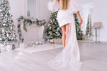 The blonde in the Christmas room. A beautiful blonde woman in a shiny light short dress with a...