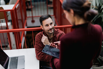 Focus on the businessman, looking at his female client, talking about some plans.