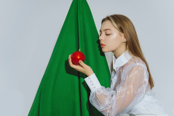 Teenage girl with red ornament in front of artificial Christmas tree