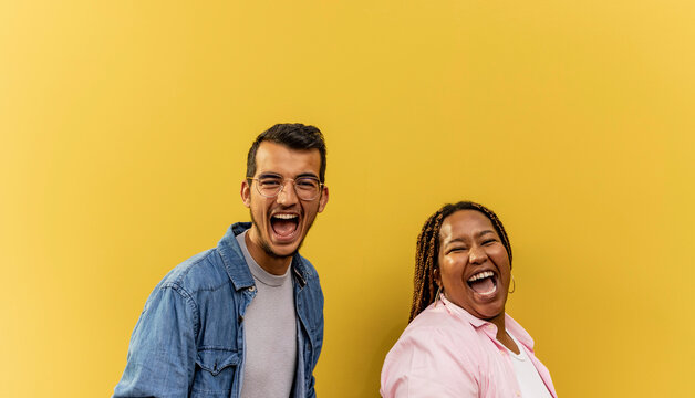Cheerful young couple screaming in front of yellow wall