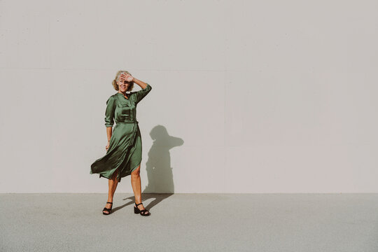 Mature woman in dress shielding eyes on sunny day