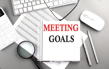 MEETING GOALS text on notepad on chart with keyboard and calculator on grey background