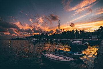 Wide-angle low-key view of a jetty on a tropical tourist island with an atmospheric sunset in the...