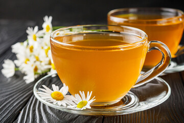 aromatic hot chamomile tea on a black rustic wooden background