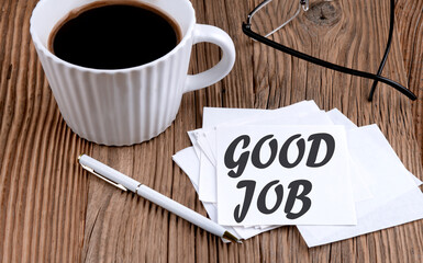 GOOD JOB text on sticky with coffee and pen on wooden background