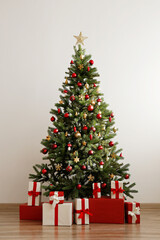 Big beautiful christmas tree decorated with shiny baubles and many different presents on wooden...