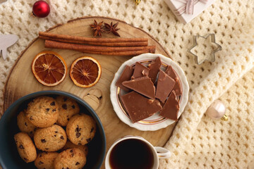 Various Christmas decorations, cup of tea or coffee, sweets, small presents, knitted blanket and candles. Flat lay.