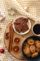 Various Christmas decorations, cup of tea or coffee, sweets, small presents, knitted blanket and candles. Flat lay.