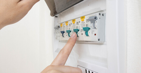 A person turns on an electric semi-automatic device with his finger to turn on the current in the electricity distribution board. 
