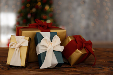 Close up shot of presents in colorful wrapping. Christmas tree with soft yellow lights, bokeh effect background. Traditional new year holiday decoration, intimate lighting. Close up, copy space.