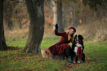 November 23, 2022. Vinnytsia, Ukraine: A girl in a burgundy coat walks with her purebred dog in autumn in the park and looks at the sky