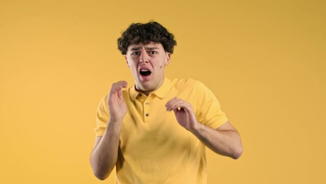 Frightened shocked man afraid of something and looks into camera with big eyes full of horror on yellow background. Phobia, trouble, panic concept.