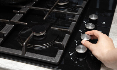 A woman turns on a gas stove with piezo ignition. Turns the gas regulator.