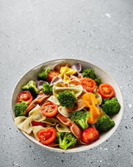 delicious colored farfalle pasta on a stone background