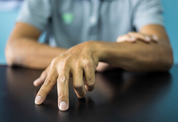 Close-up front view of both hands of a thai man wearing gray shirt making various gestures.