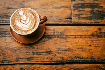 A cup of cappuccino with a beautiful pattern in the froth photographed from above on a rustic...