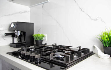 Modern kitchen with gas hob against white granite tiles. Decoration pots with artificial flowers. Copy space for text