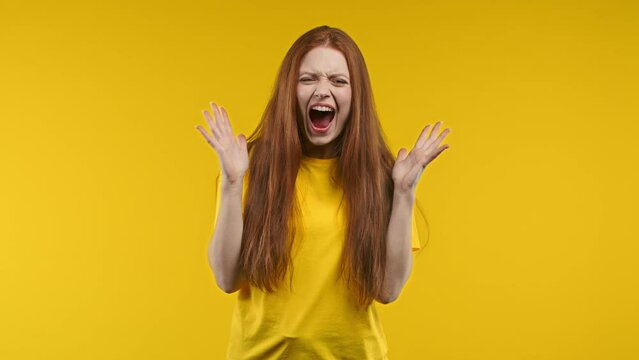 Frightened shocked woman afraid of something and screaming into camera with big eyes full of horror on yellow background. Phobia, trouble, panic concept.