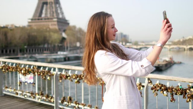 Girl taking selfie near the Eiffel tower with her smartphone in Paris, France