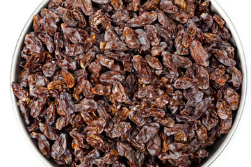 Dark-colored raisins lying in a metal container, shot on a white background.