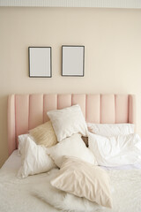 Warm and cozy interior of bedding room space with pink bed, mock up poster frame. Cozy home decor.
