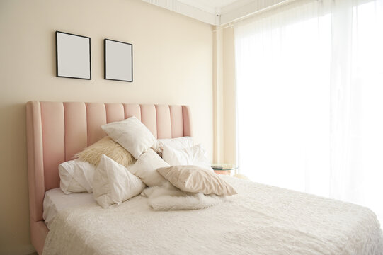 Warm and cozy interior of bedding room space with pink bed, mock up poster frame. Cozy home decor.