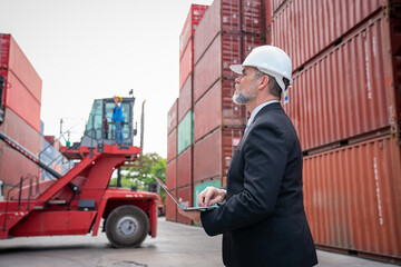 Container yard manager with safety hat checking container at container yard warehouse. Import and export concept.