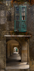 Old green wooden window and below street passage through columns of the old town of Pontevedra