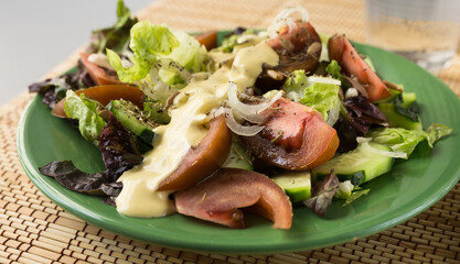 vegetable salad of greens, tomatoes and cucumbers on a green plate