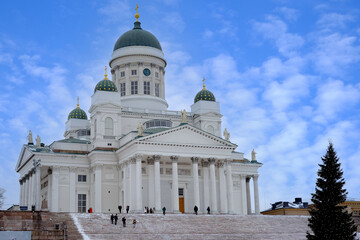 Fototapeta premium view of Helsinki Cathedral of St. Nicholas on Senate Square, people walking along winter street, decorated Christmas tree, concept holiday, pre-holiday chores citizens, tourists Finland