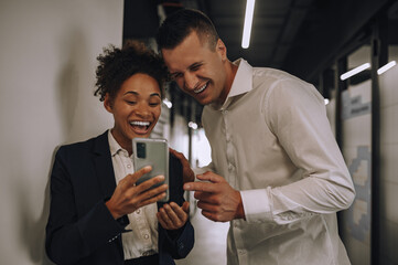 Laughing woman and man looking at smartphone screen