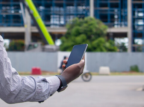 Jeune homme africain tenant un smartphone sur un chantier de construction