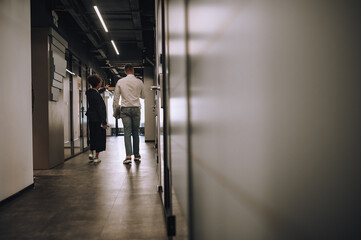 Man and woman walking corridor with backs to camera