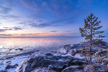 Sunset over icy rocks and frozen sea. Pörkenäs, Finland