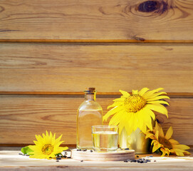 Sunflower oil in a bottle glass with seeds and sunflower on wooden background