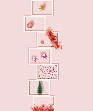 White frames decorated with pink Christmas ornaments, gift box and tree on bright paste pink background. Flat lay advent season concept. Creative New Year idea.