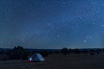 A tent under a star-filled night sky in the Grand Staircase-Escalante National Monument, a few miles south of the town of Escalante, Utah. Fiftymile Mountain is seen in the distance.