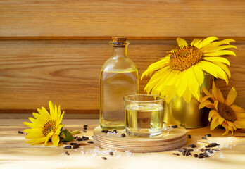 Close-up of sunflower oil in a bottle glass with seeds, salt and sunflower on wooden background