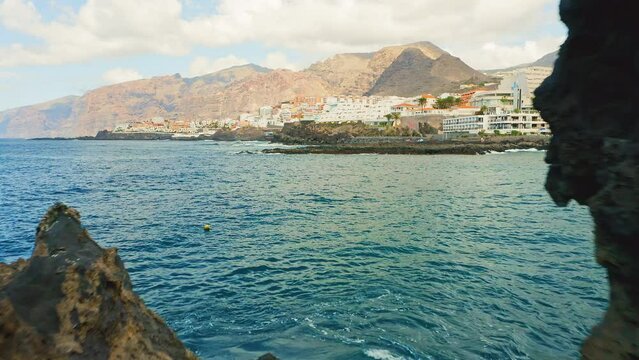 Aerial flight walk through dangerous rocks natural ocean swimming pool of Devil. Frozen black lava flows, volcanic bizzare stones, rocky beach. Tenerife Canary Islands. Charco El Diablo.