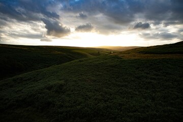 Scenic view of hills covered with green field at a cloudy sunset in Scotland